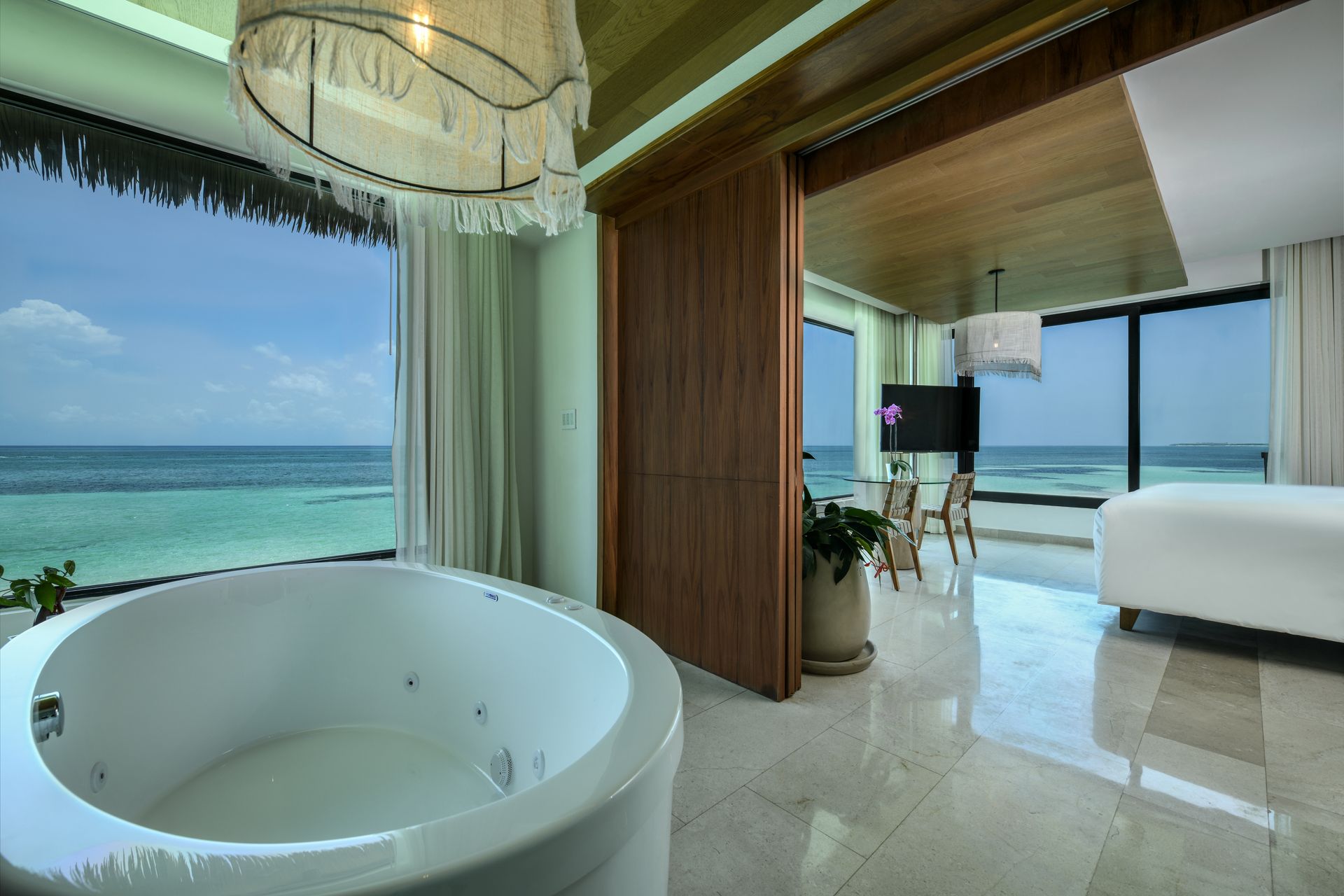 Luxury suite with jacuzzi overlooking turquoise ocean.