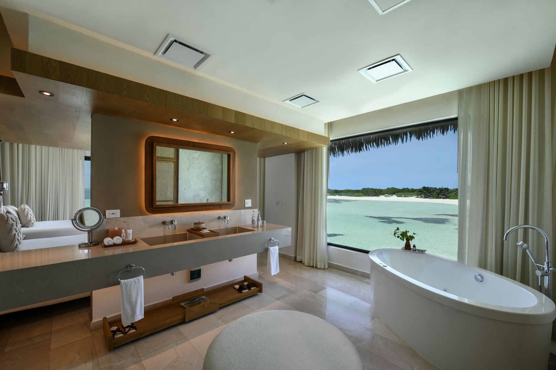 Luxurious bathroom with ocean view, featuring a bathtub, vanity, and large window.