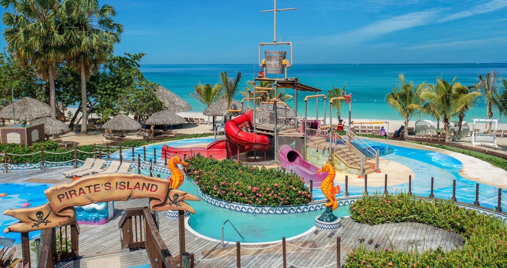 Pirate's Island water park with slides, pool, and a beach backdrop, tropical setting.