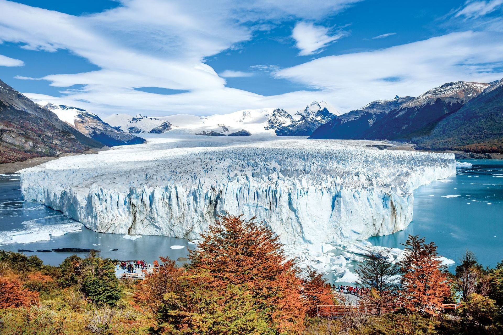 Glacier Perito Moreno in Argentina, turquoise water, snow-capped mountains, and colorful autumn trees.