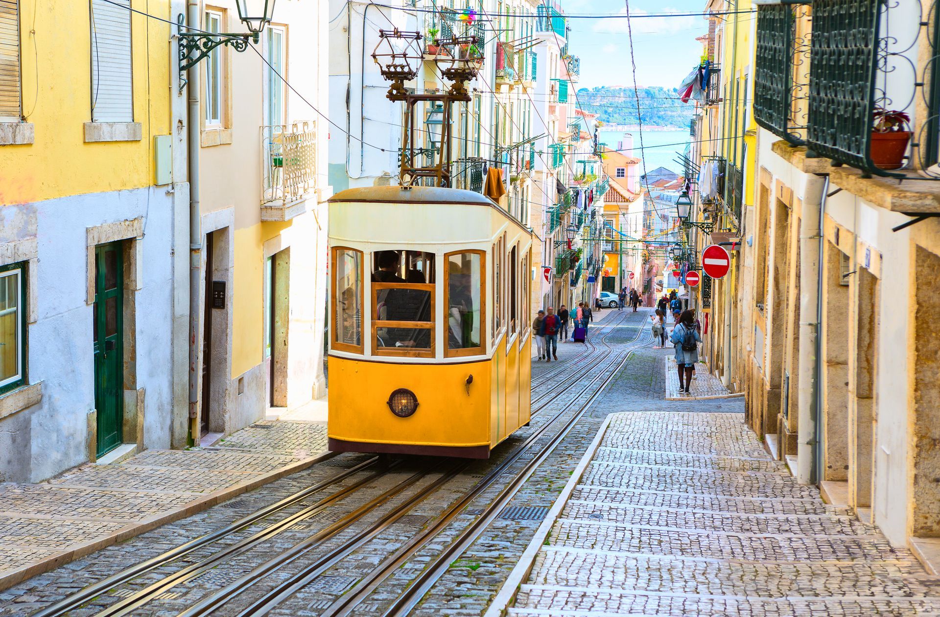 Historic yellow tram on narrow Lisbon street in Portugal