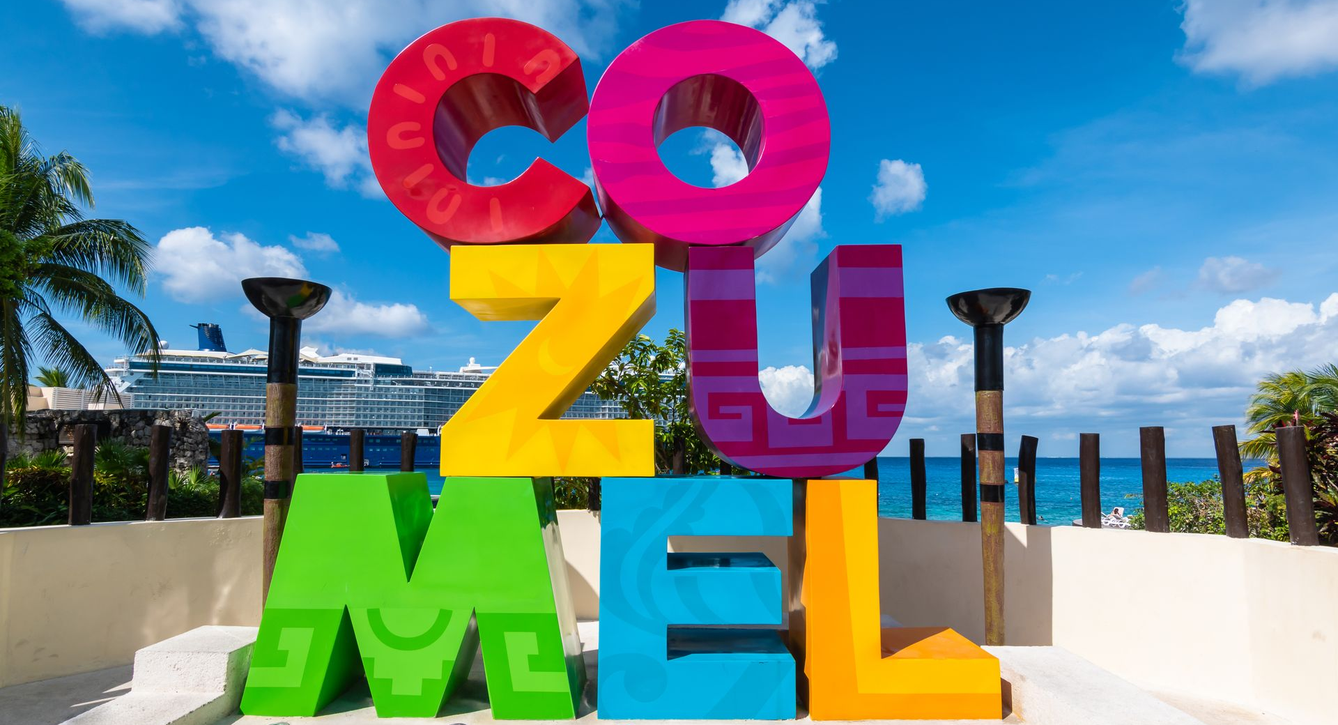 Colorful Cozumel letters along the waterfront in Mexico, with palm trees, and the Caribbean
