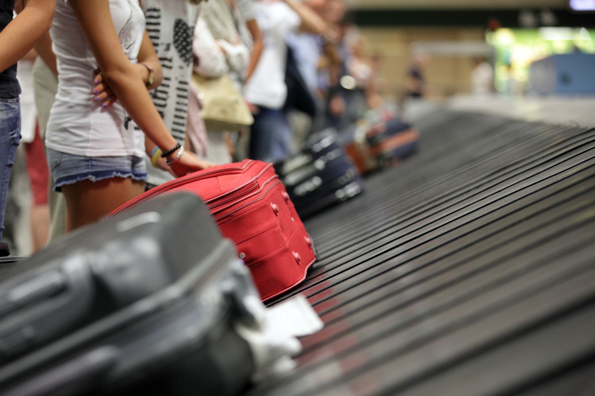 Red suitcase among other luggage on an airport baggage carousel