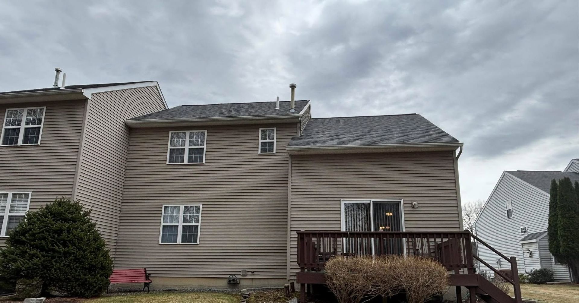 Gray townhouse with wood siding, front deck, and overcast sky