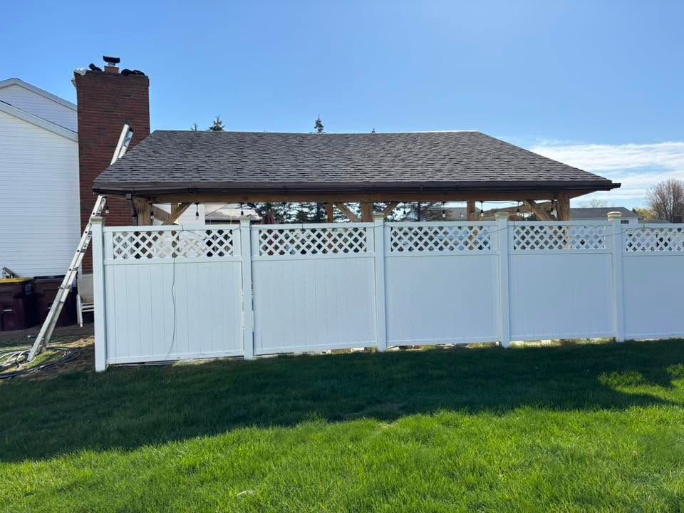 White fenced patio with lattice gate beside a brick chimney and house under a blue sky