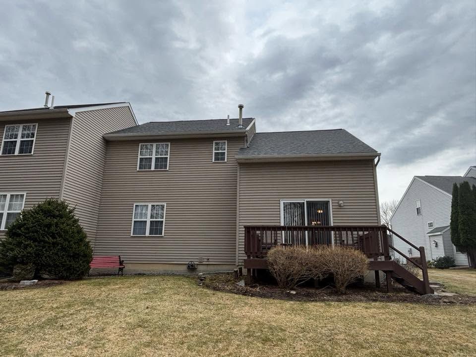 Suburban house with beige siding, deck, and cloudy sky