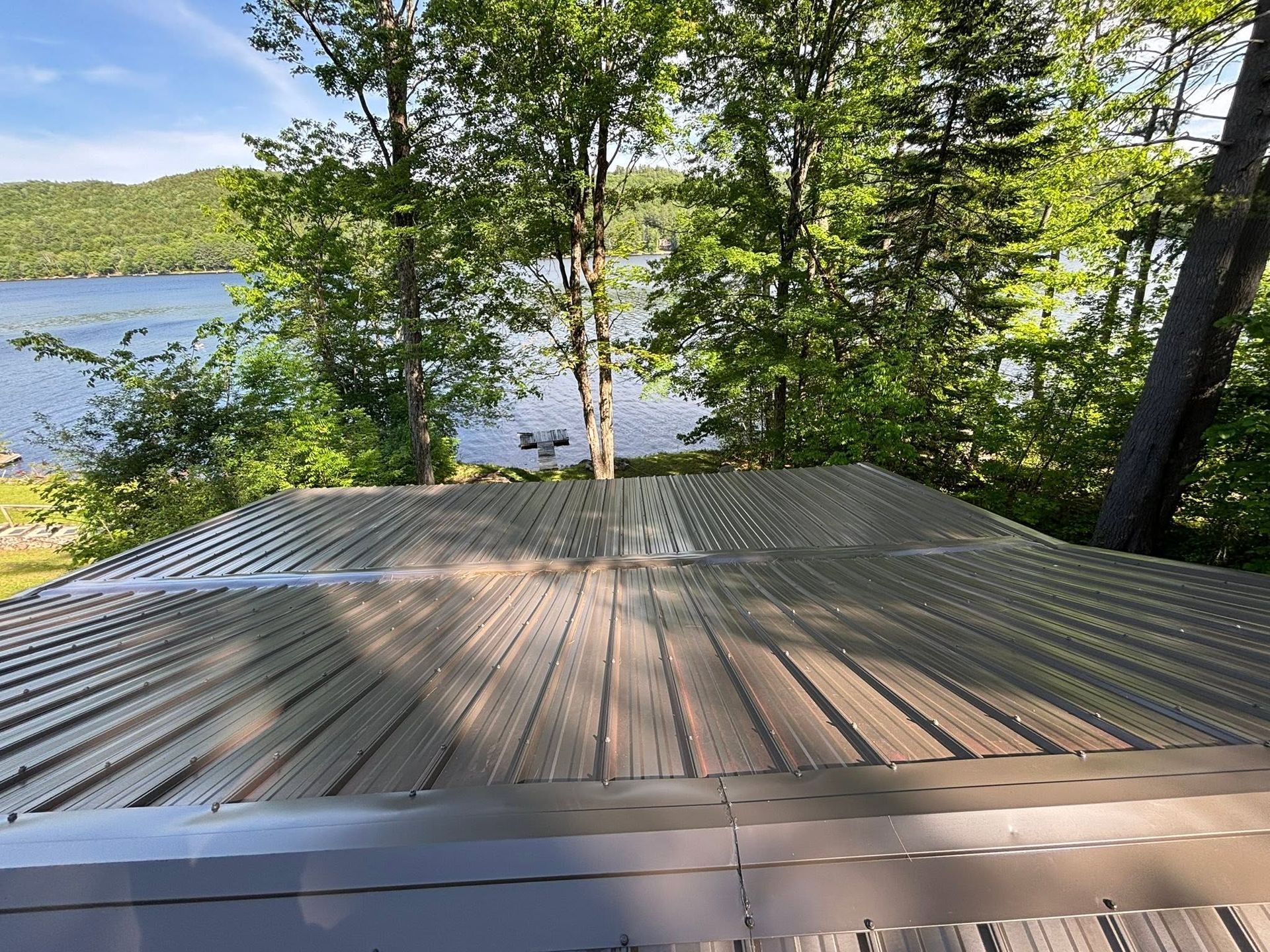 Wooden deck overlooking a lake through leafy trees on a sunny day