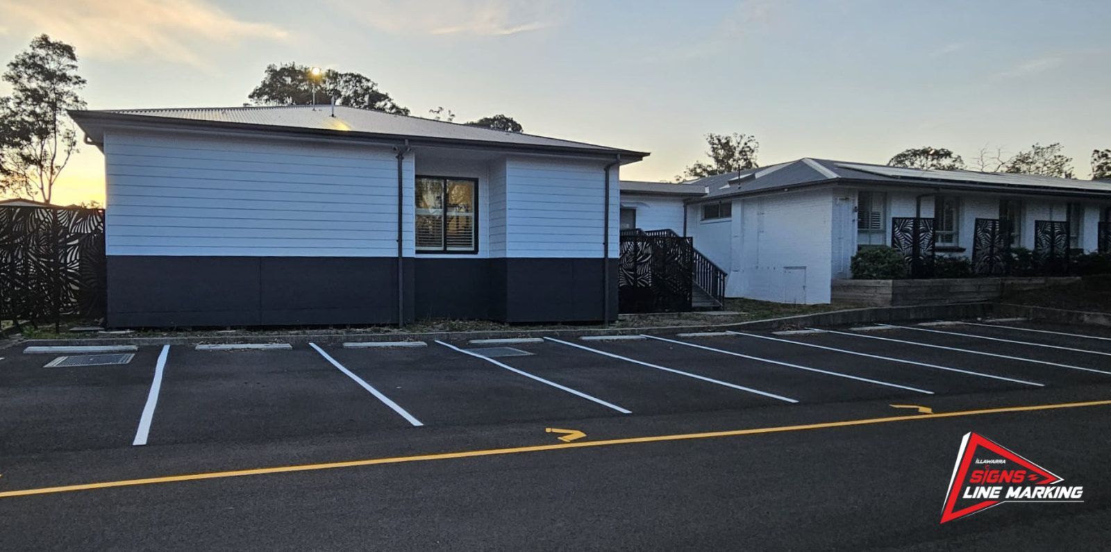 White car spaces, a yellow aisle line and yellow arrows in a newly marked car park