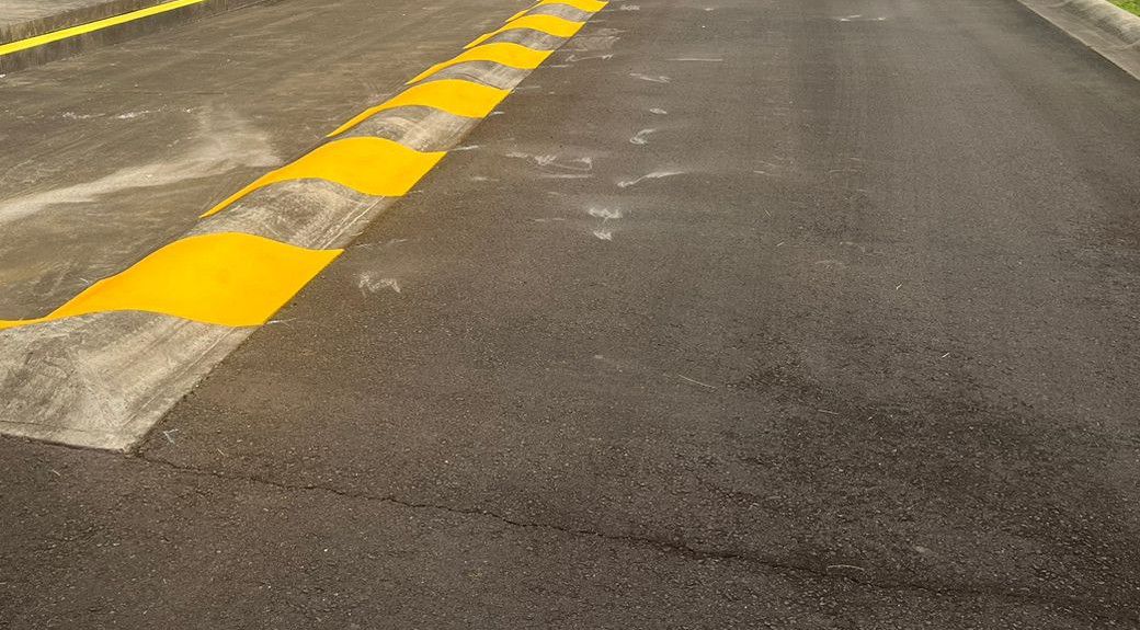 Yellow chevron lines on a concrete bund beside a site road