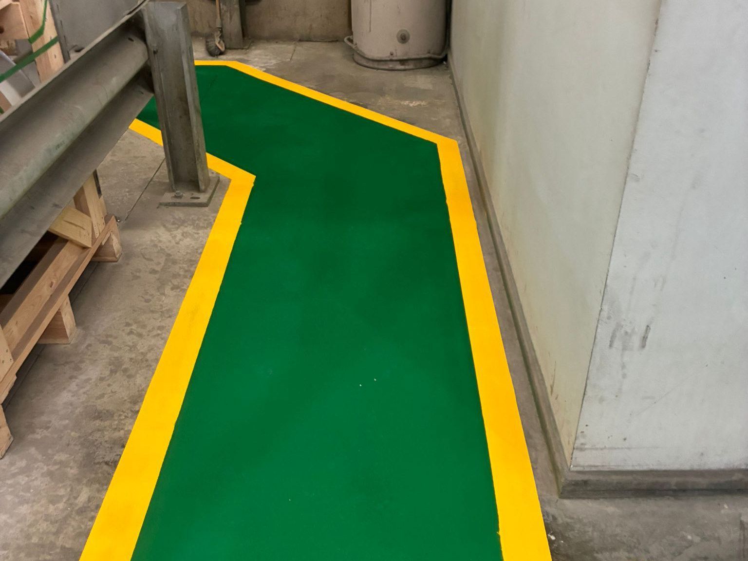 Green walkway with yellow edge lines around a guard rail