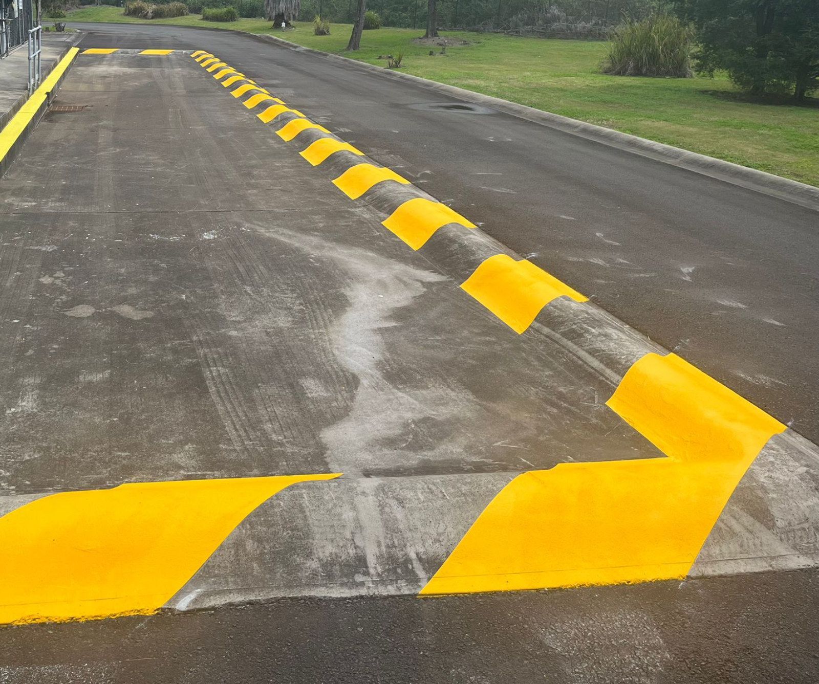 Yellow chevron humps and edge line beside a dosing area at a water plant