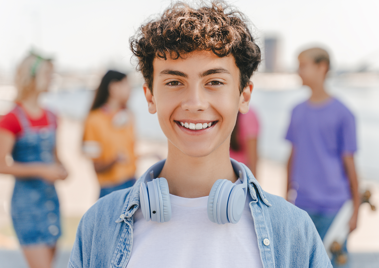 Un joven que lleva auriculares sonríe delante de un grupo de jóvenes.