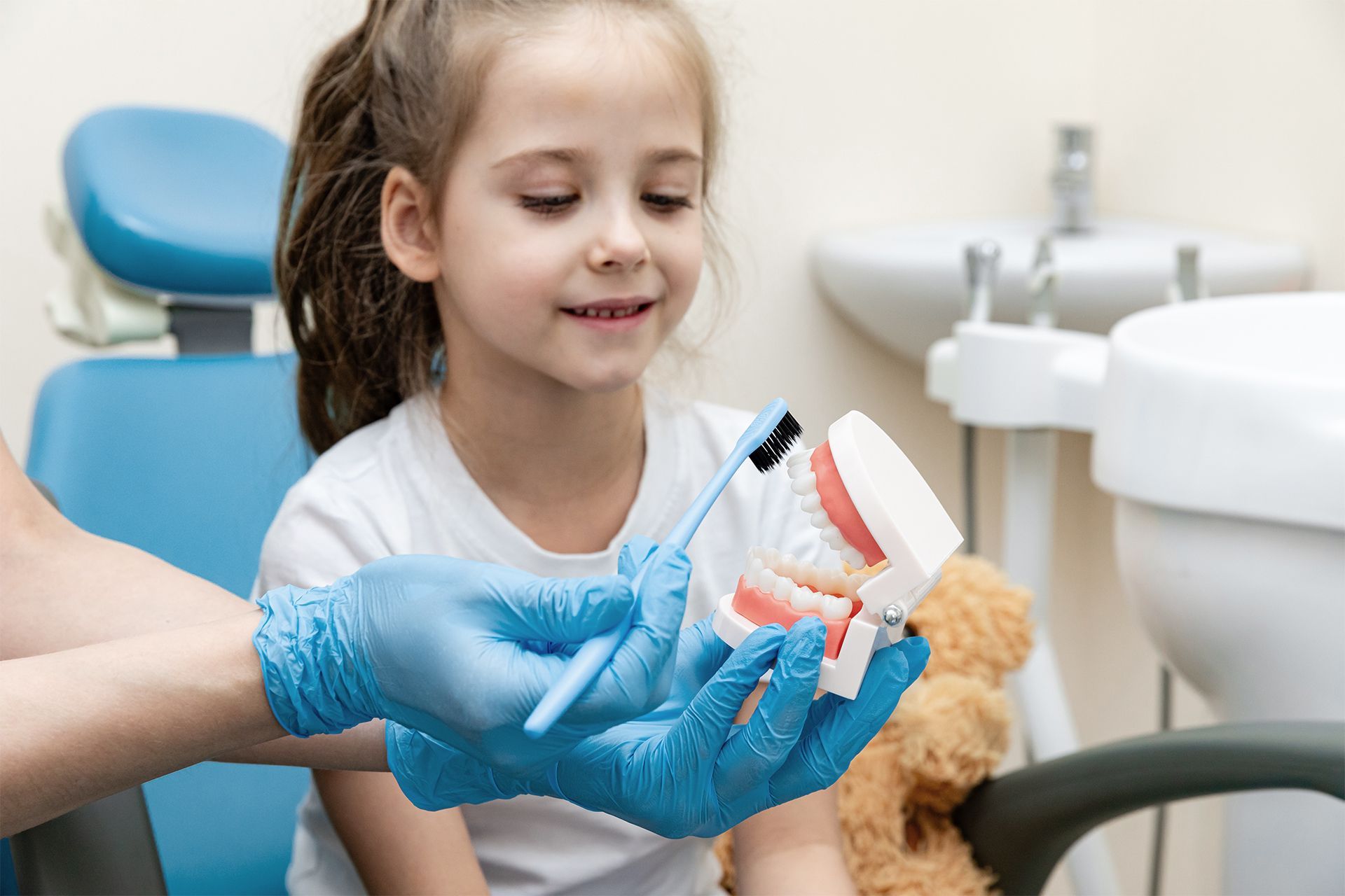 Una niña se cepilla los dientes con un cepillo de dientes en un consultorio dental.