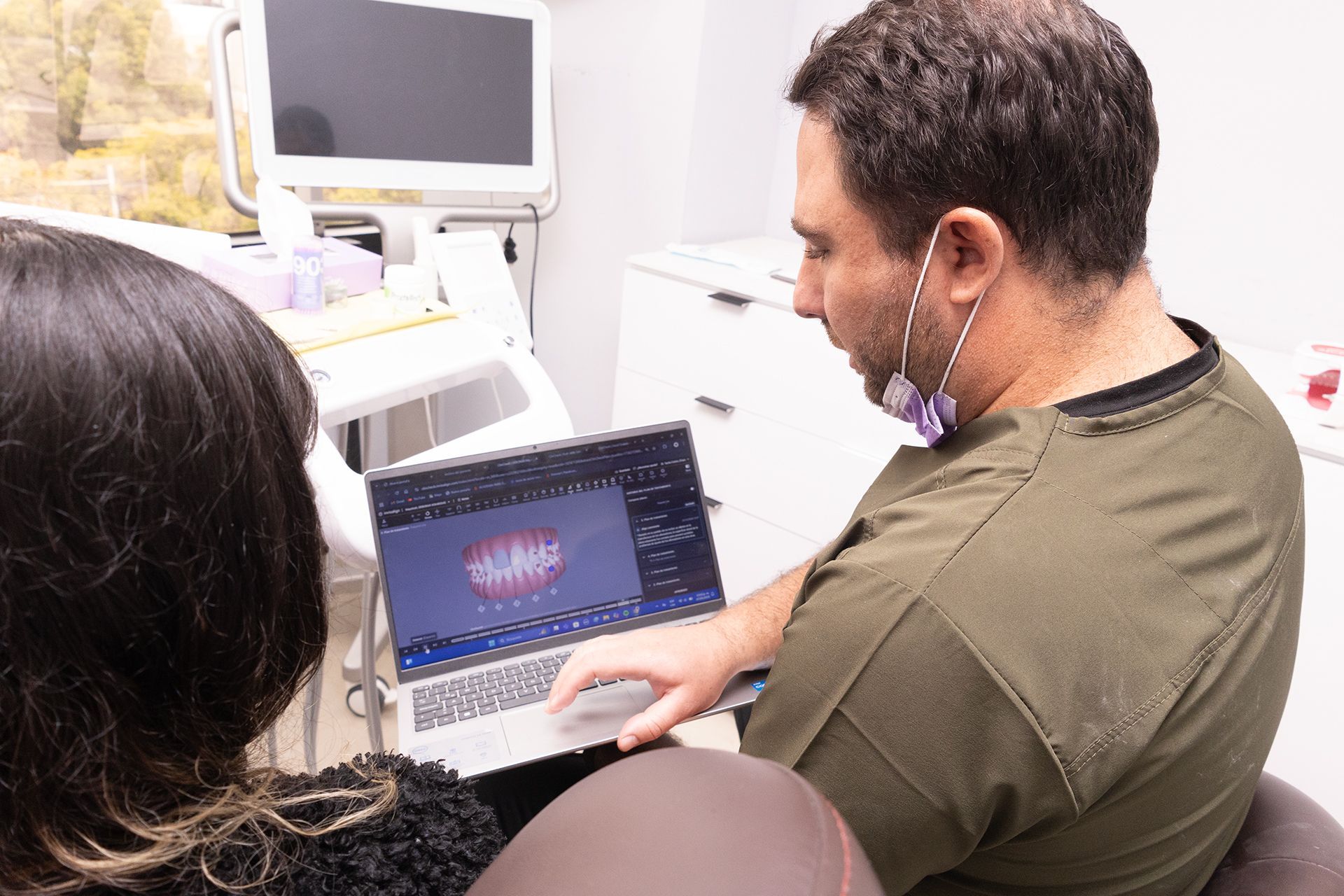 Un hombre y una mujer miran una computadora portátil en un consultorio dental.