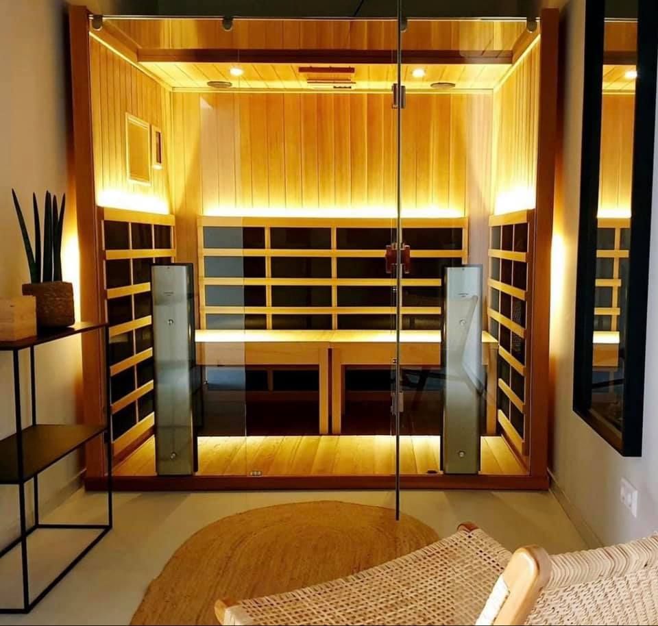 A wooden sauna with a glass door and a chair