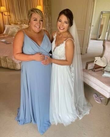 A bride and her bridesmaid are posing for a picture in a room.