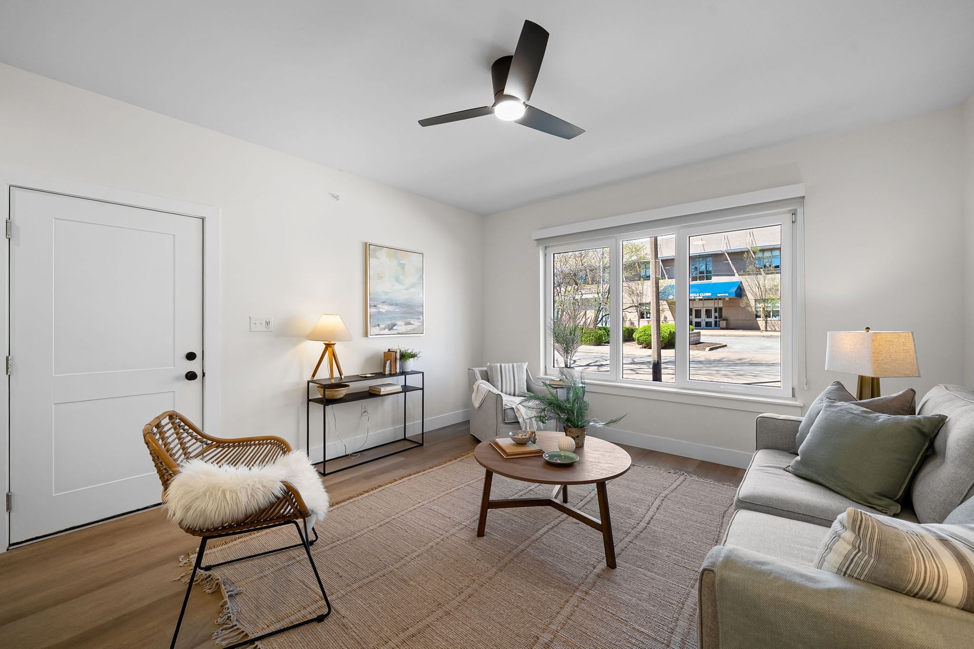 Bright living room with gray sofa, round coffee table, armchair, and large window view