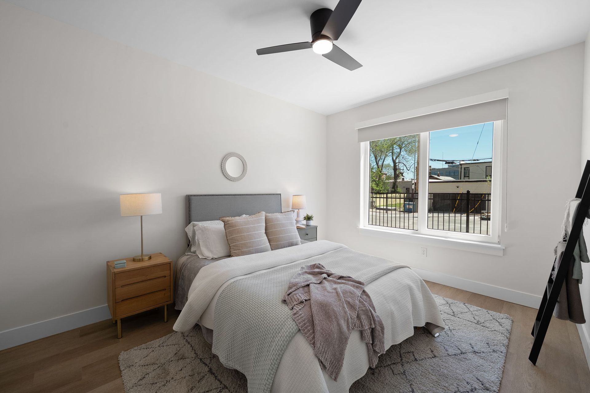 Bright bedroom with a bed, nightstands, lamps, ceiling fan, and a window with daylight.