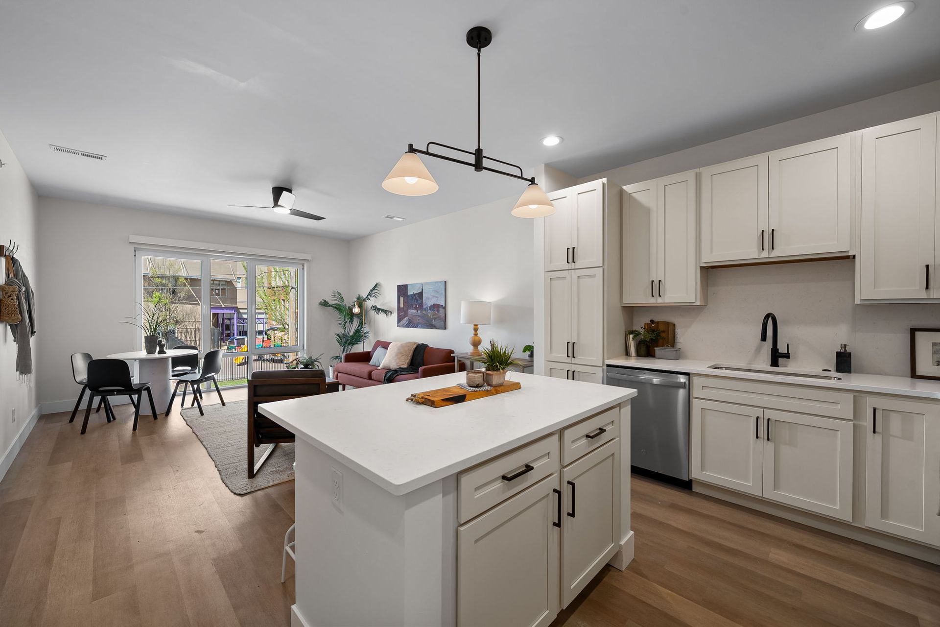 Bright modern kitchen with white cabinets, island, and dining area opening to a patio.