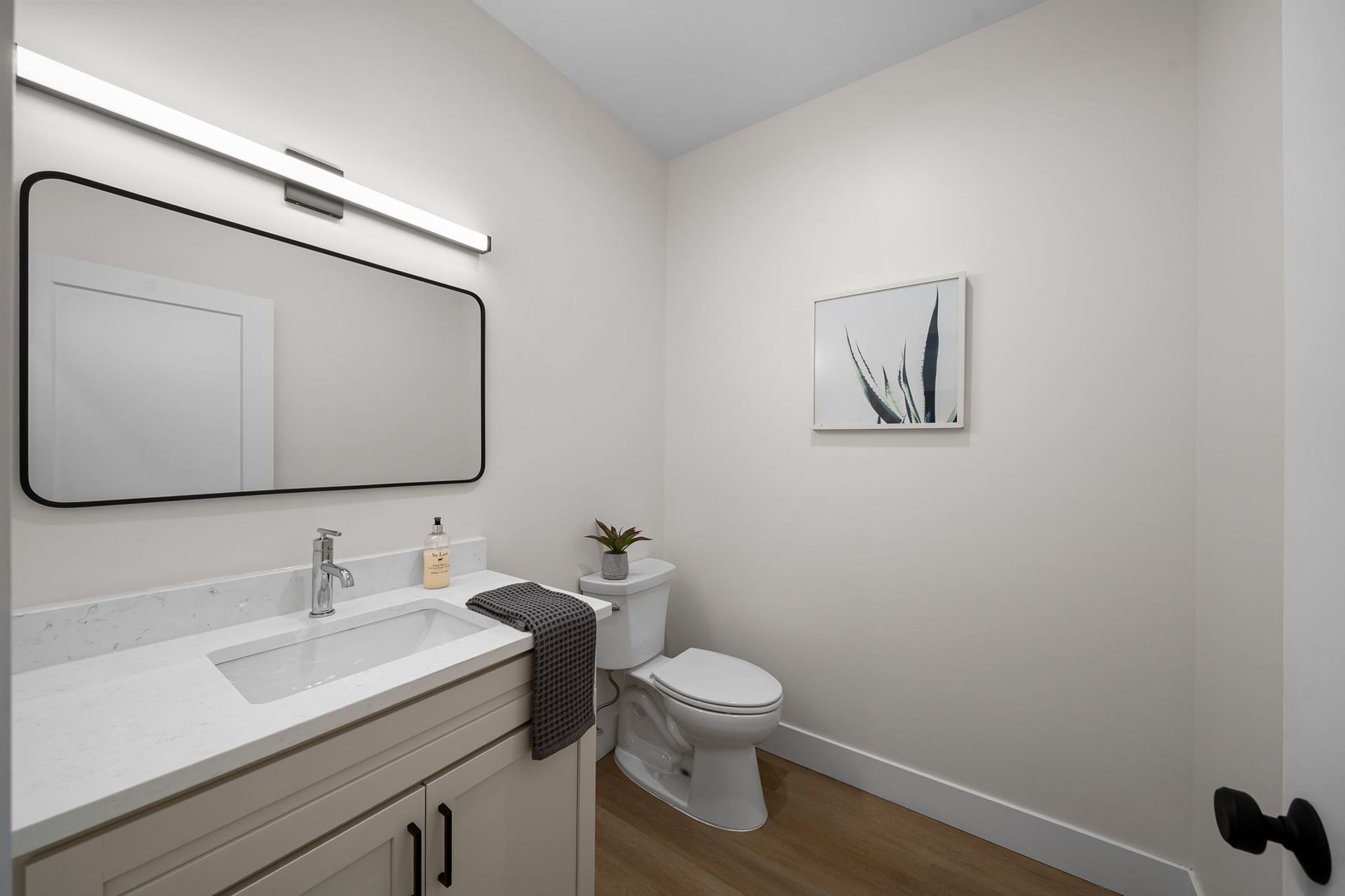 Modern bathroom with vanity, large mirror, toilet, and minimalist wall art.