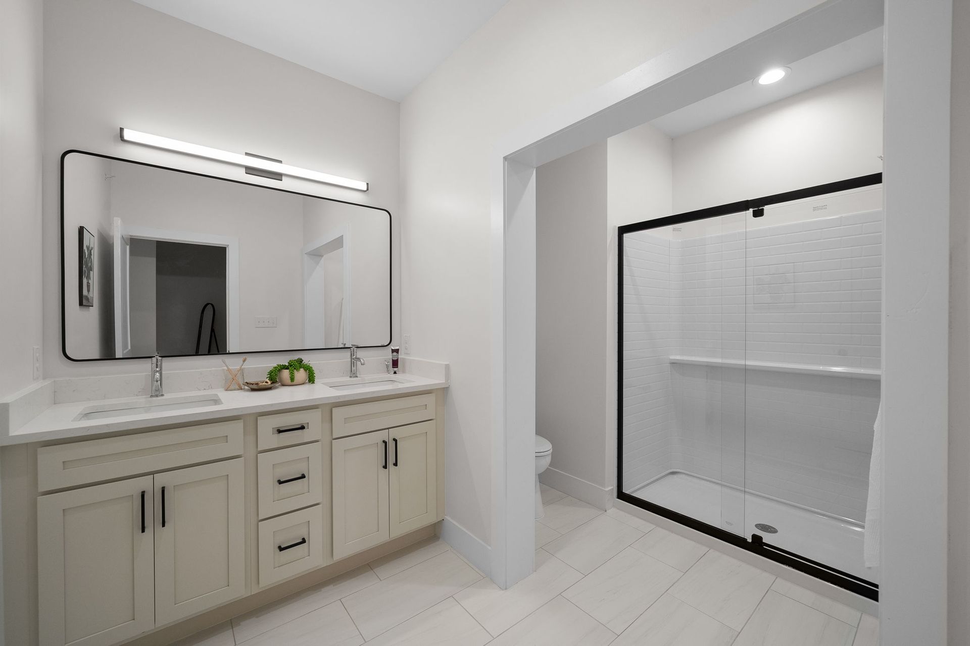 Modern bathroom with double vanity, large mirror, and glass shower enclosure