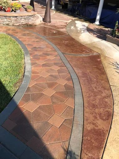 Curved brick and stone walkway in a landscaped garden with grass and flower beds