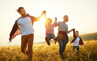 A family is walking through a field holding hands.