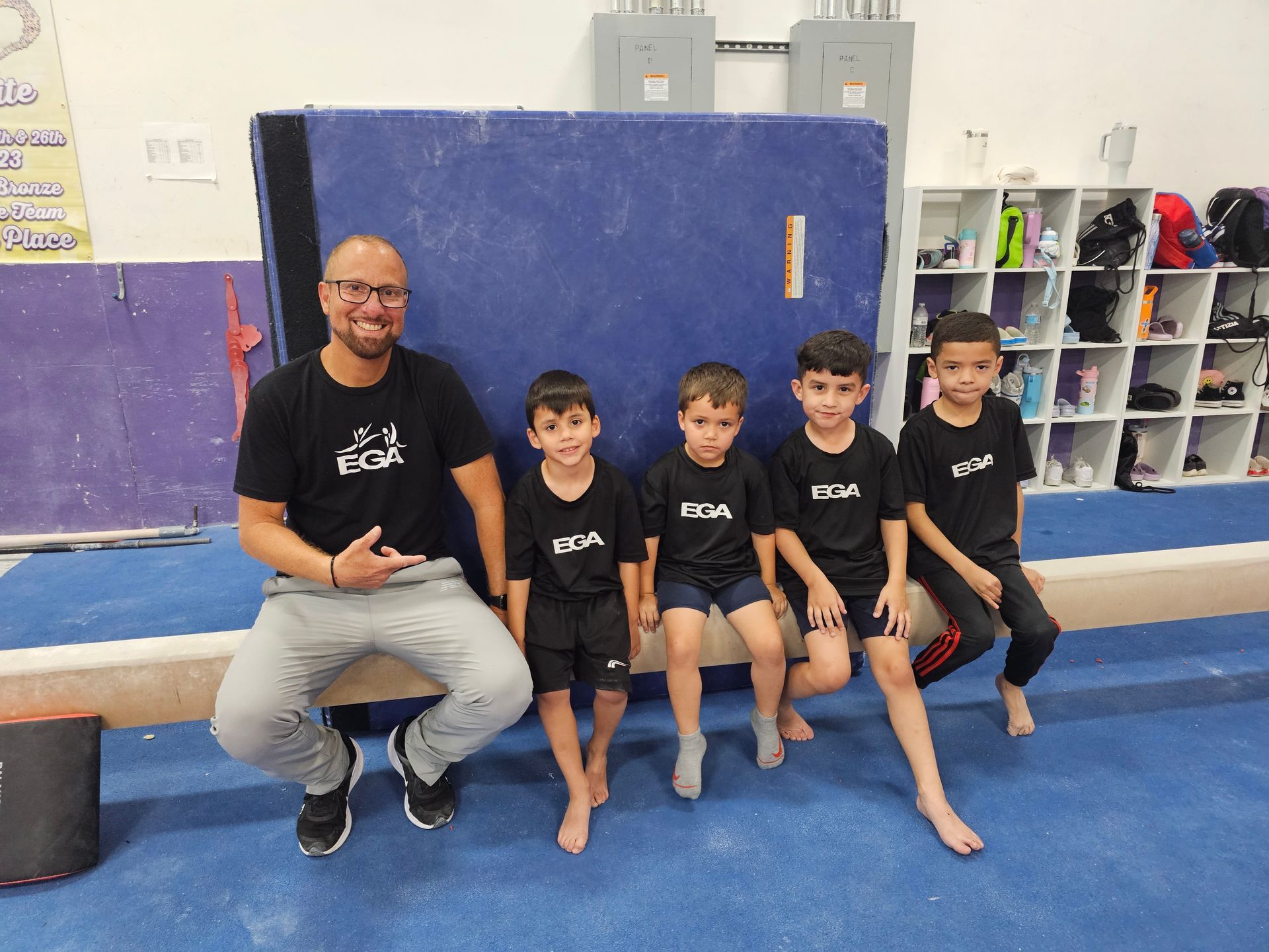 Un hombre y tres niños están sentados en una viga de equilibrio.
