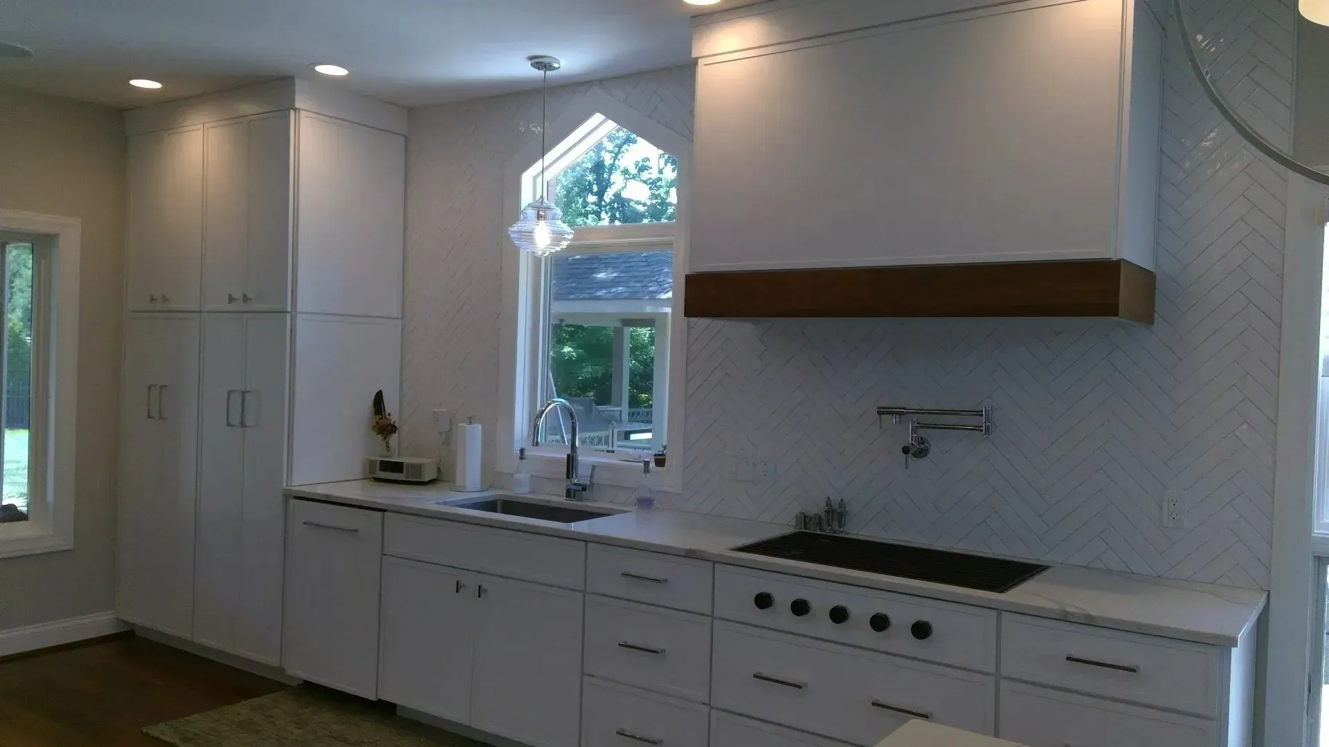 A kitchen with white cabinets , a sink , and a window.