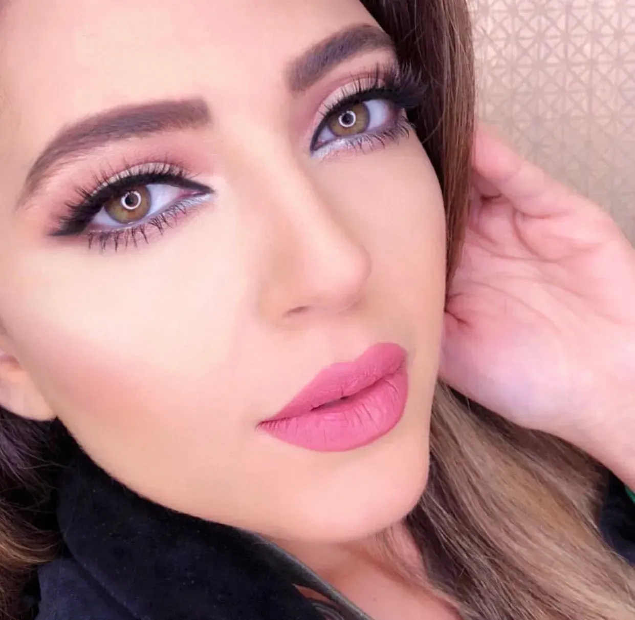 Woman with full face makeup, pink lipstick, and brown eye shadow.