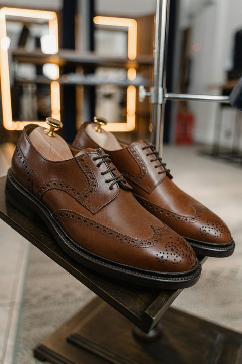 Scarpe eleganti in pelle marrone esposte su un supporto in una boutique.