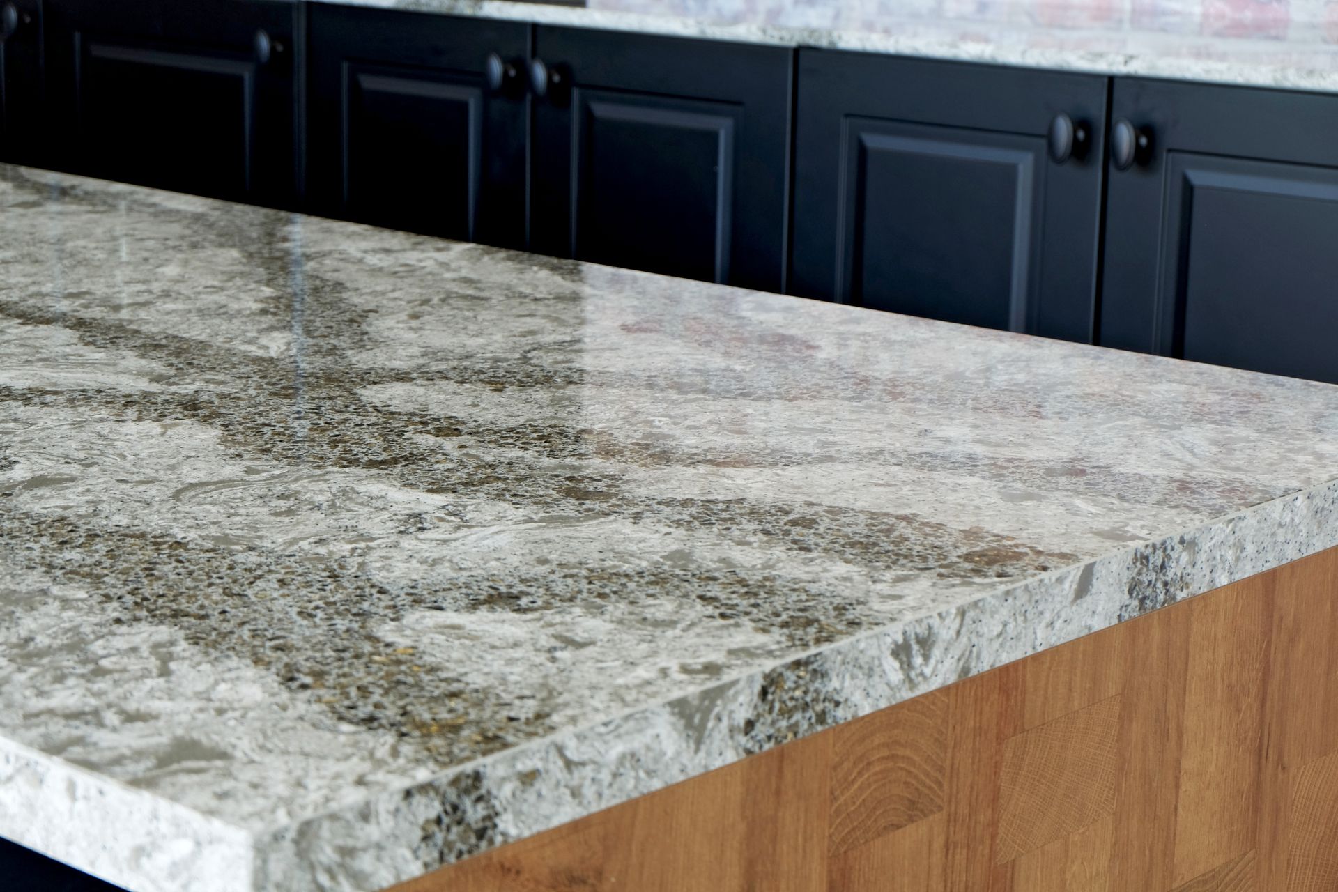 Gray granite kitchen island countertop with dark cabinets in the background