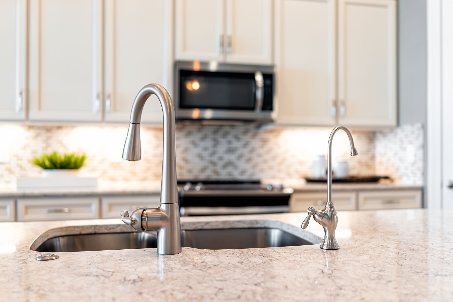 Modern white kitchen with marble island, pale cabinets, and warm under-cabinet lighting