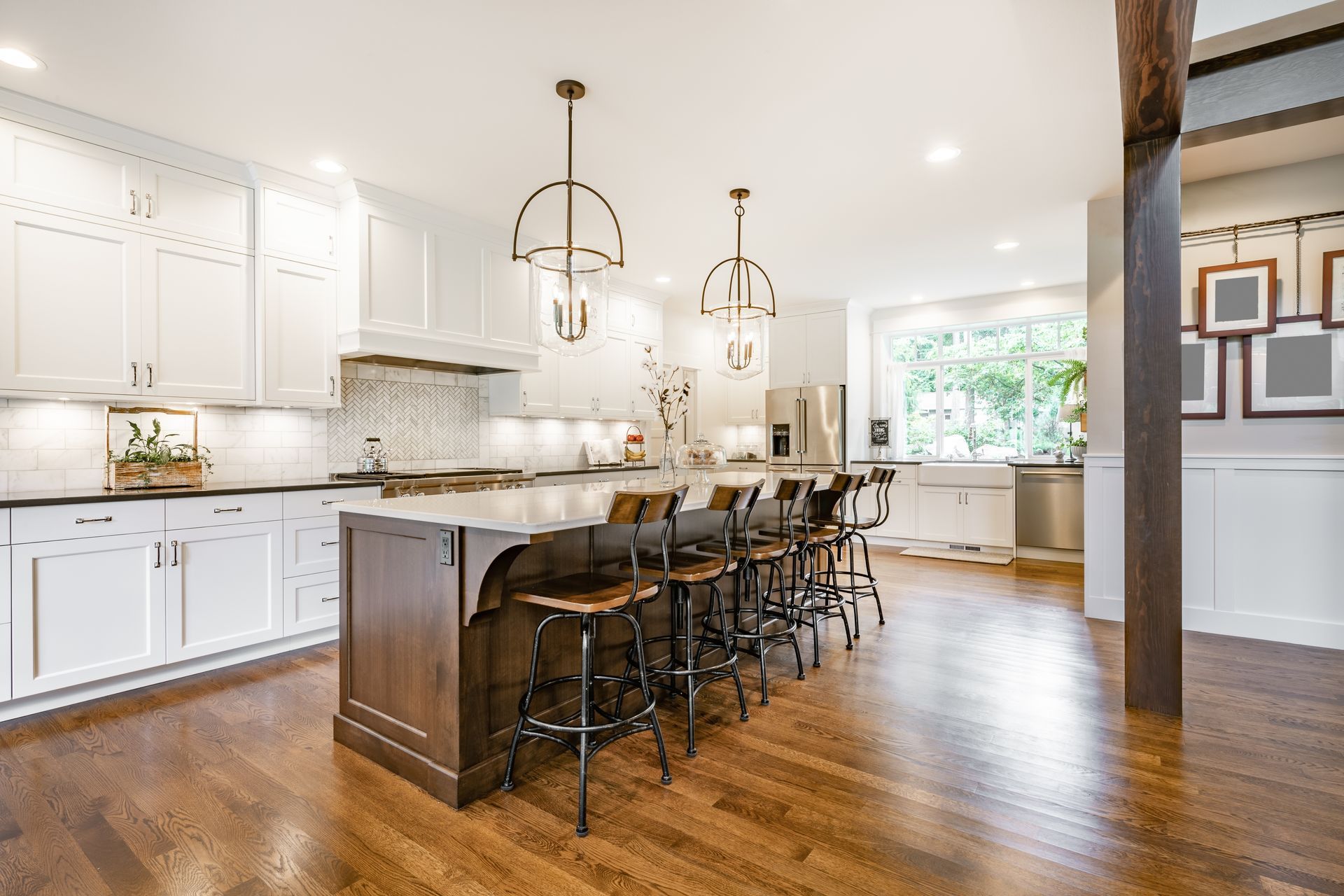 Bright modern kitchen with white cabinets, wood island, bar stools, and hardwood floors