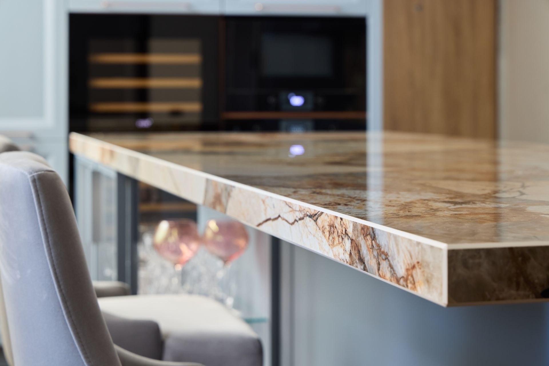 Marble kitchen island countertop with modern built-in wine fridge in the background