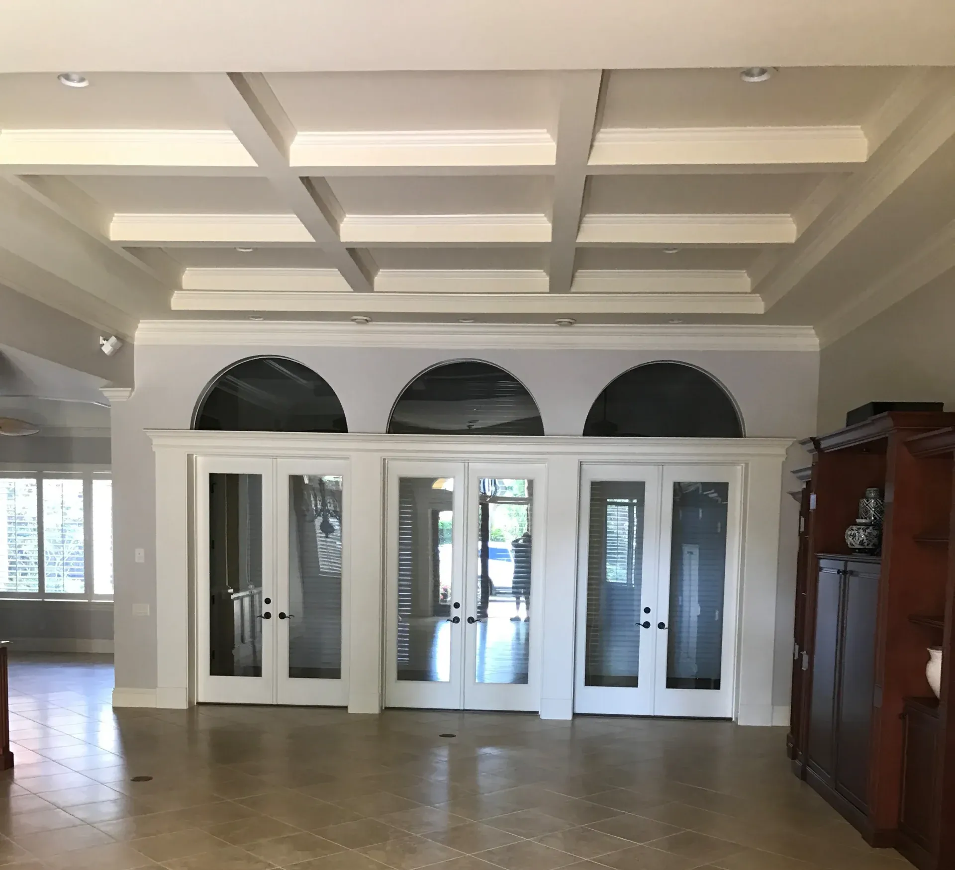 Entryway with arched openings above glass doors and a coffered ceiling.