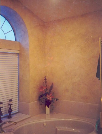 Bathroom with a large tub, beige walls, arch window, and flowers.
