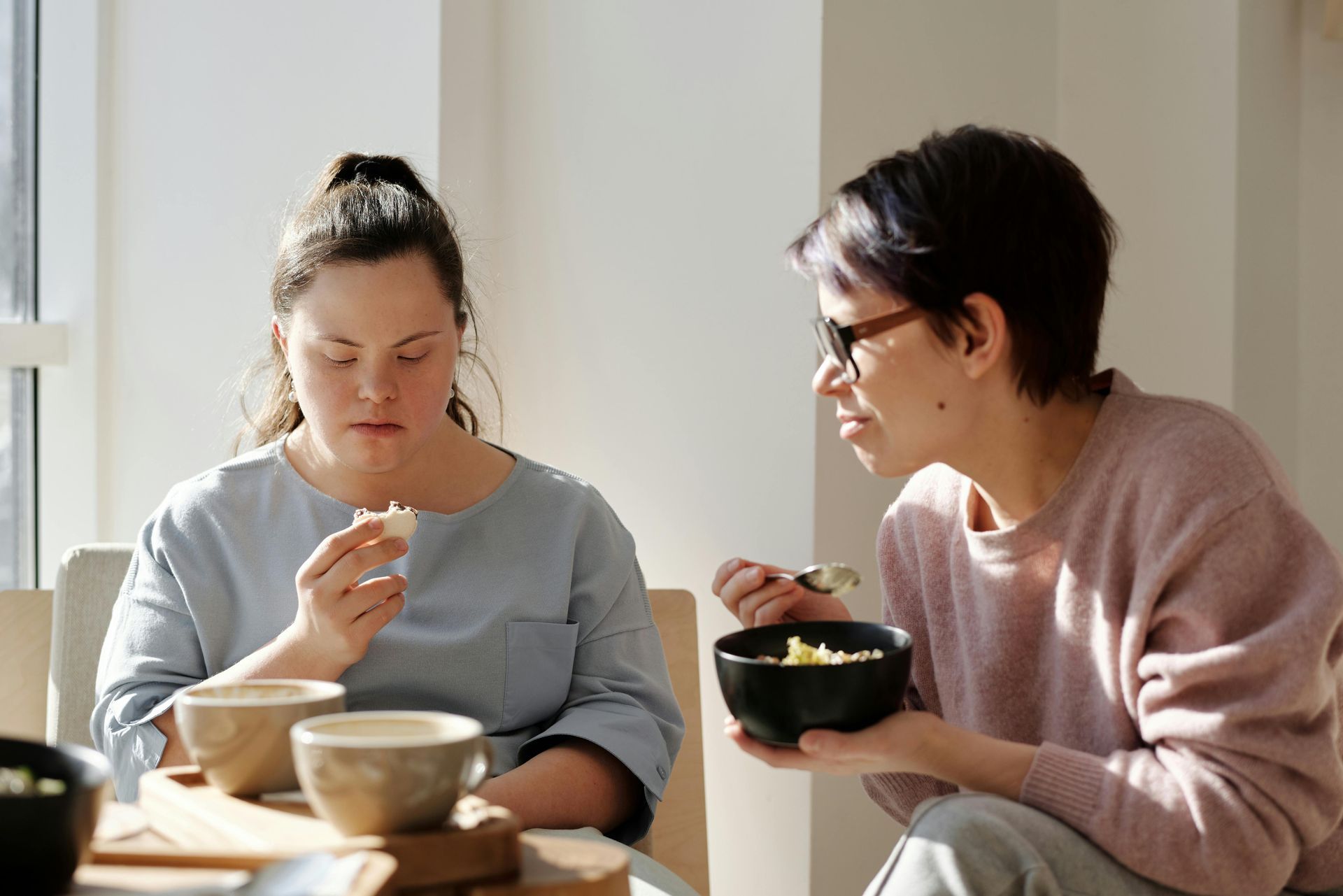 Two people sitting at a table eating a meal together in a bright, indoor setting.