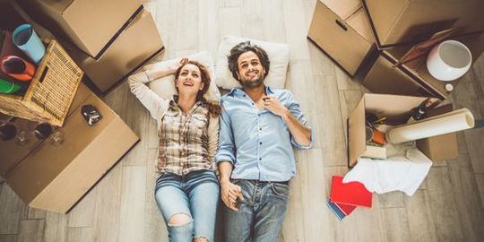 Picture of a couple holding hands and laying down in new home.