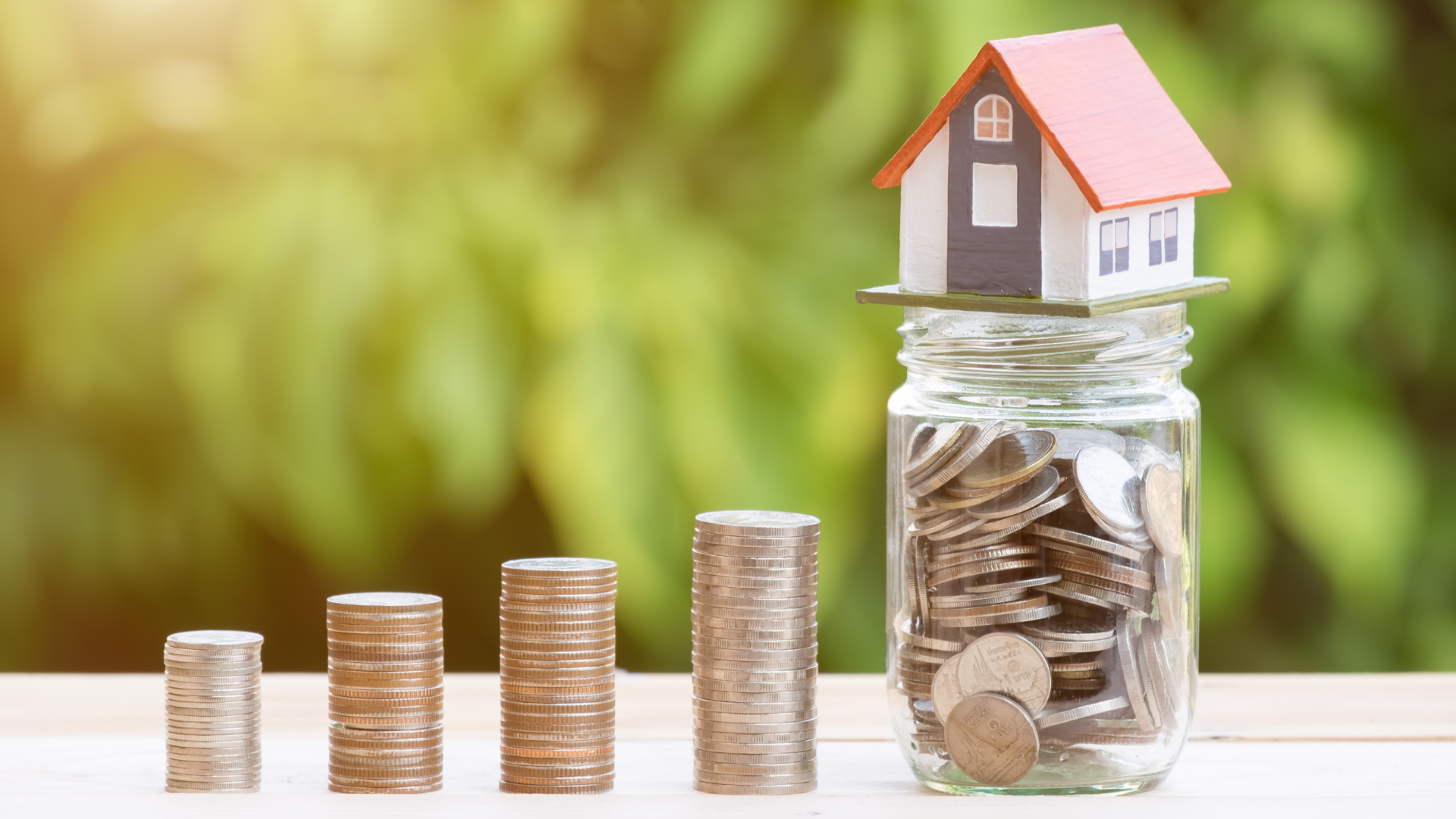 Jar of coins with a toy house on top.