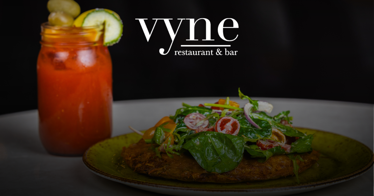 Vyne restaurant dish with a colorful plated entree and a tomato cocktail garnished with cucumber slice