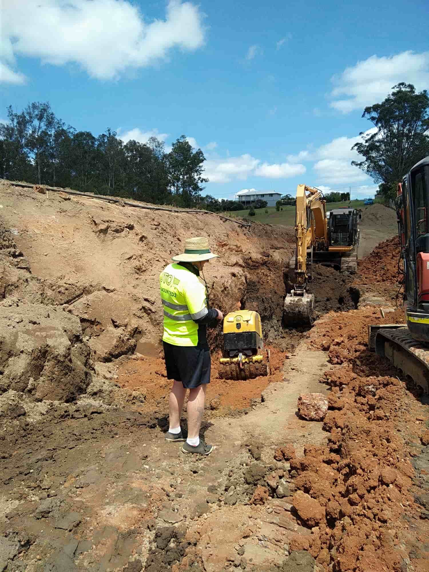 A Man Is Standing In The Dirt Next To A Bulldozer — Ant's Earthworks In North Deep Creek, QLD