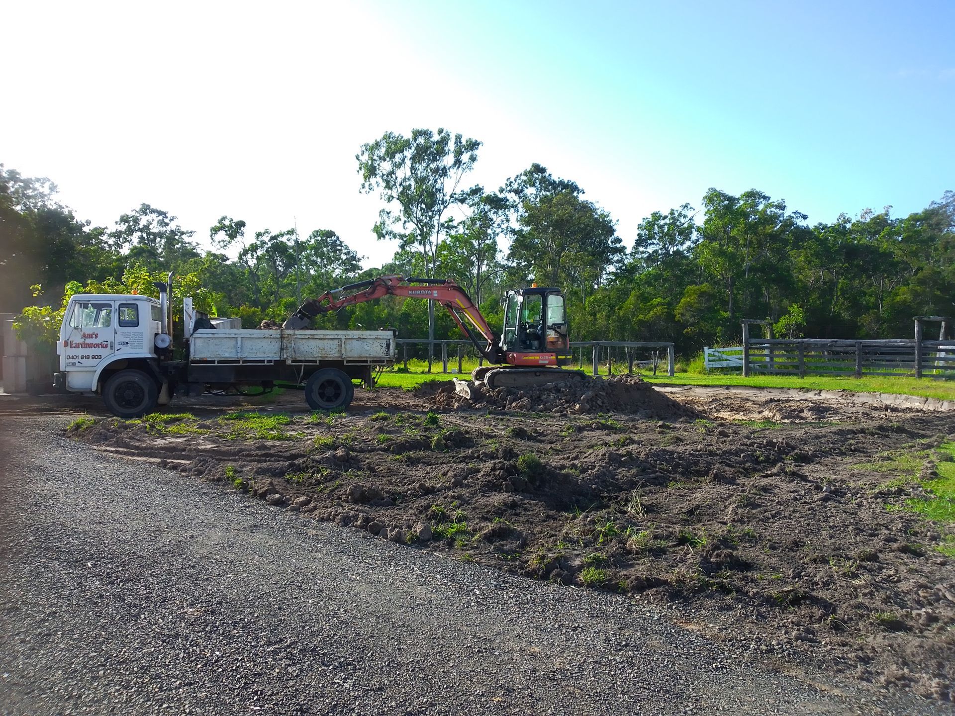 A Red Digger Is Putting Dirt In The Back Of A Truck— Ant's Earthworks In North Deep Creek, QLD 