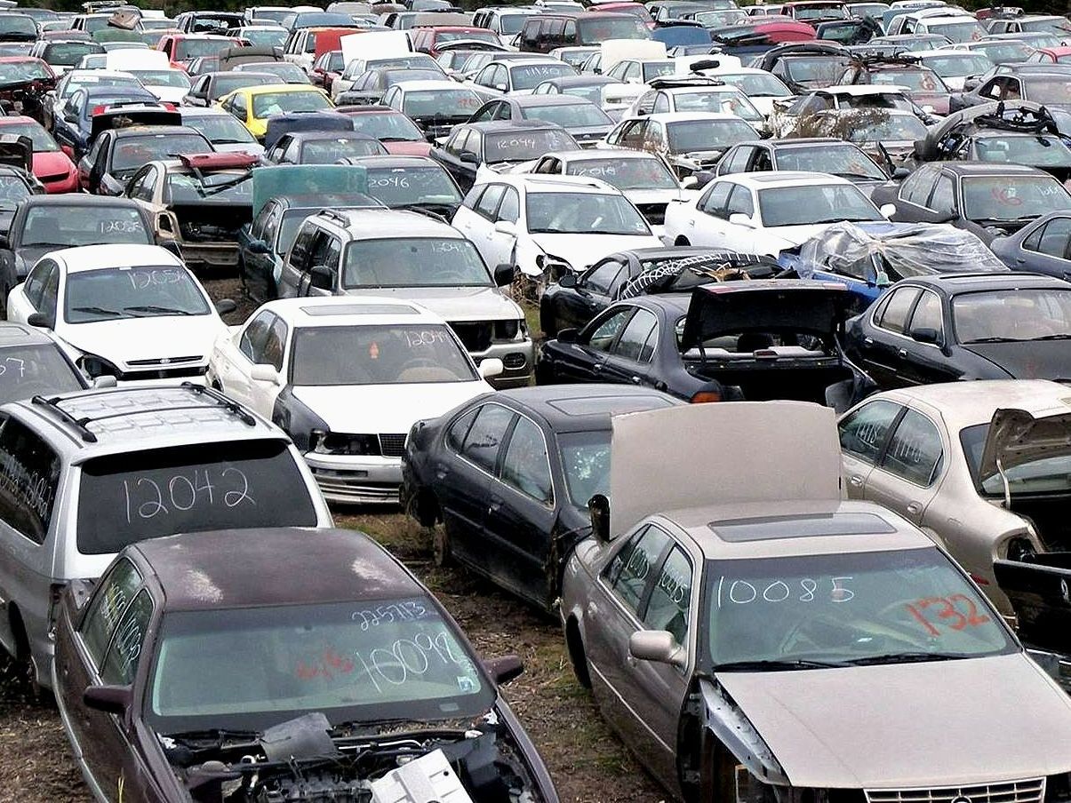A lot of cars are parked in a lot including a bmw