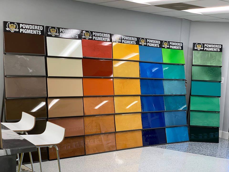 Wall of paint color samples in a showroom, arranged in rows from neutral tones to bright blues and greens.