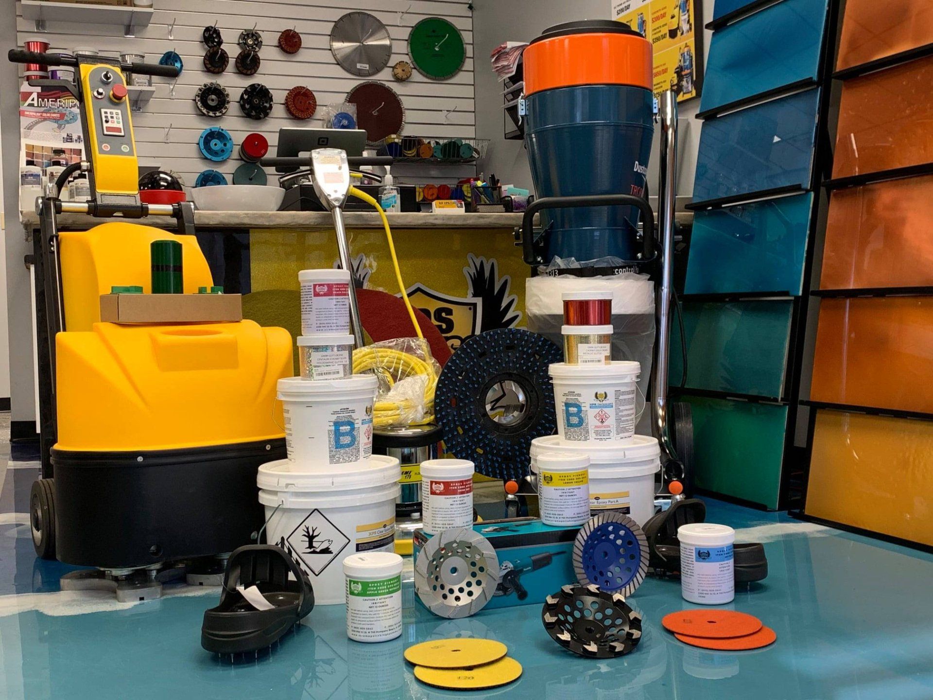 Industrial tools and cleaning supplies displayed in a workshop, with a yellow machine and colorful storage bins.