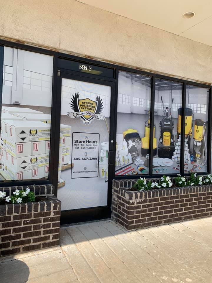 Shop storefront with black door, large window display, and brick planters outside