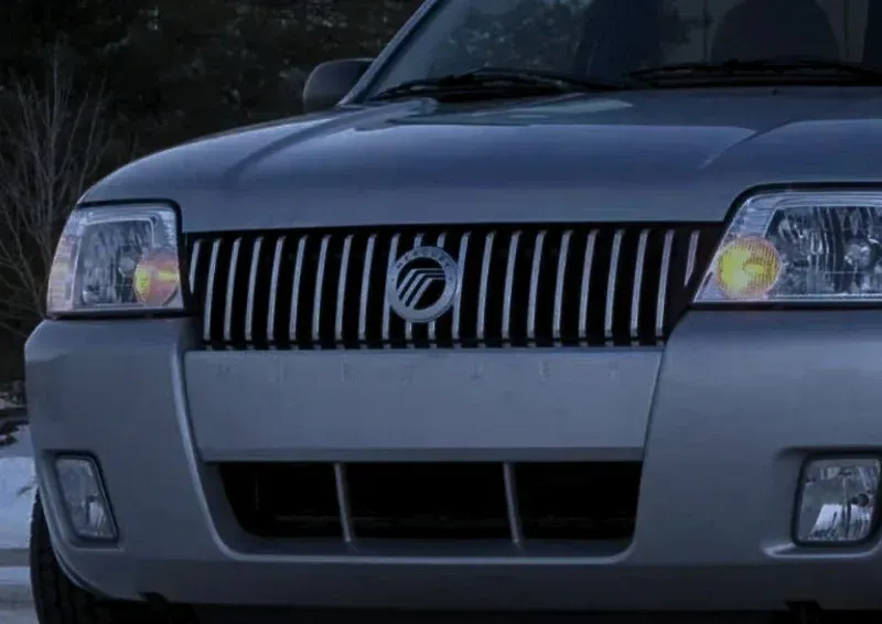 Front view of a silver SUV with a vertical grille and headlights, parked outdoors