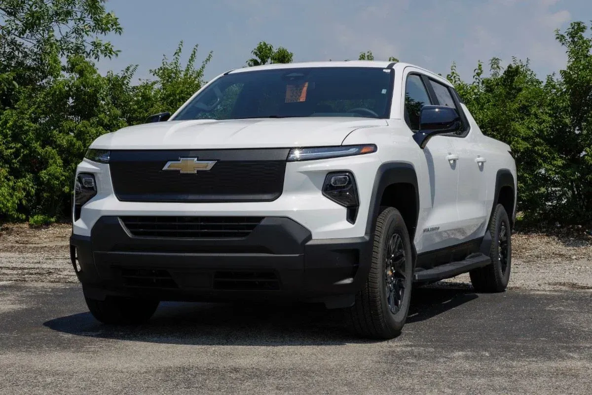 White Chevrolet pickup truck parked outdoors on a gravel lot under a clear sky