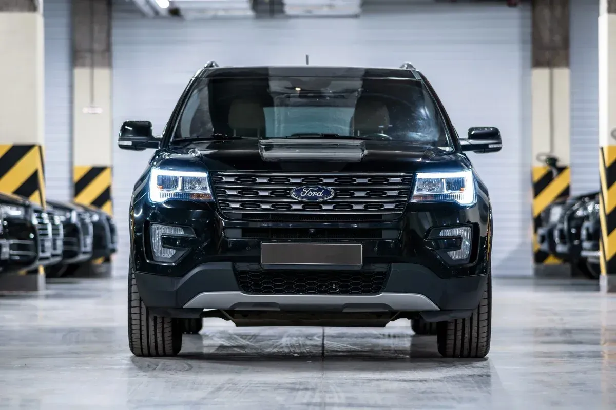 Black pickup truck parked in a warehouse garage, front view with headlights on.